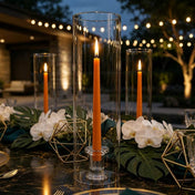 Outdoor evening tablescape with orange taper candles in glass cylinder vases - thumbnail number 3