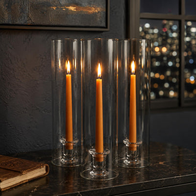 Elegant lit taper candles in clear glass vases with city lights background - thumbnail number 7