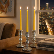 Yellow taper candles in silver holders beside city view window - thumbnail number 6