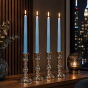 Light blue taper candles in silver holders on modern table by city window at night - thumbnail number 6