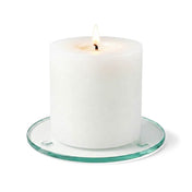 A lit white pillar candle on a clear glass Round Coaster 4" against a white backdrop - thumbnail number 3