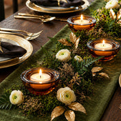 Amber glass tealights with white flowers and gold leaves on a green mossy table runner - thumbnail number 4