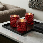 Three red honeycomb votive holders with candles on black tray in cozy living room - thumbnail number 6