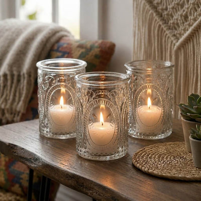 Three glowing candles in glass holders on rustic table with cozy boho decor - thumbnail number 7