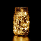 Mason jar filled with warm white fairy lights glowing in the dark.  - thumbnail number 1