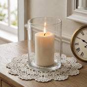 A lit white pillar candle in a Wide Cylinder Vase sitting on a crocheted doily beside a clock - thumbnail number 7