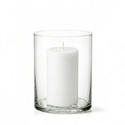An unlit white pillar candle centered inside a clear glass Wide Cylinder Vase on white - thumbnail number 2