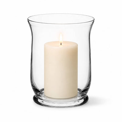 A lit white pillar candle burning inside a clear glass Hurricane Vase on a white backdrop - thumbnail number 3
