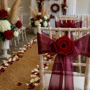White chairs adorned with burgundy sashes and burgundy red preserved roses for a wedding aisle - thumbnail number 4
