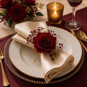 A burgundy red preserved rose adorns a folded napkin on a plate at a table setting - thumbnail number 5