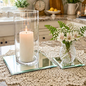 A lit candle in a glass holder and a small flower vase on mirrored coasters on a kitchen counter - thumbnail number 8