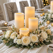 A floral centerpiece with white roses and ivory flameless LED pillar candles on a table - thumbnail number 6