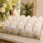 A gold tray displaying white 5x7in muslin favor bags with thank-you tags at a wedding reception - thumbnail number 3