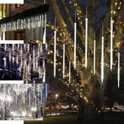 Decorative hanging LED light tubes illuminating tree branches at night. - thumbnail number 1
