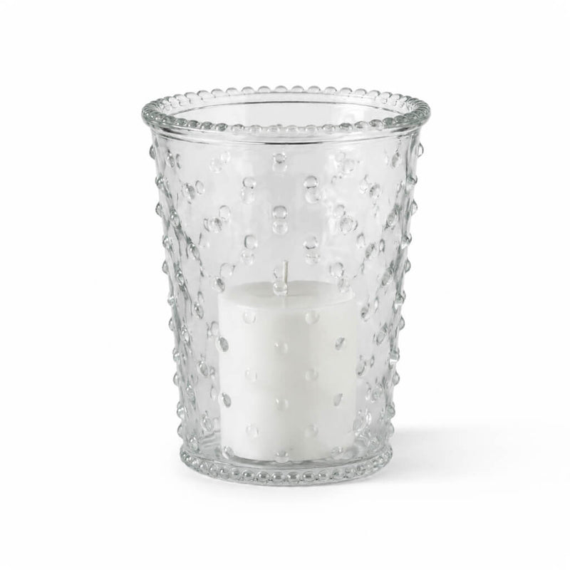 An unlit white pillar candle inside a clear glass Hobnail Candle Holder on a white studio backdrop - thumbnail number 2