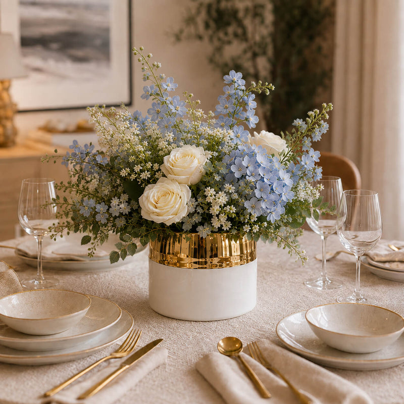 7.5" x 6.25" white and gold ceramic Claire vase holding a blue and white floral arrangement on a dining table - thumbnail number 7