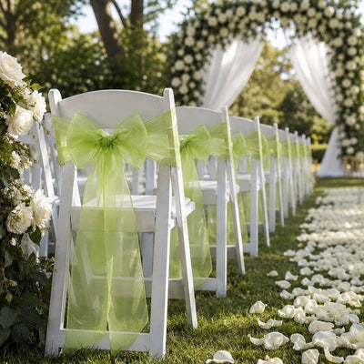 White chairs with sage organza sashes lining an outdoor wedding aisle - thumbnail number 5