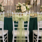 White chairs with sage organza sashes at a green draped table - thumbnail number 2