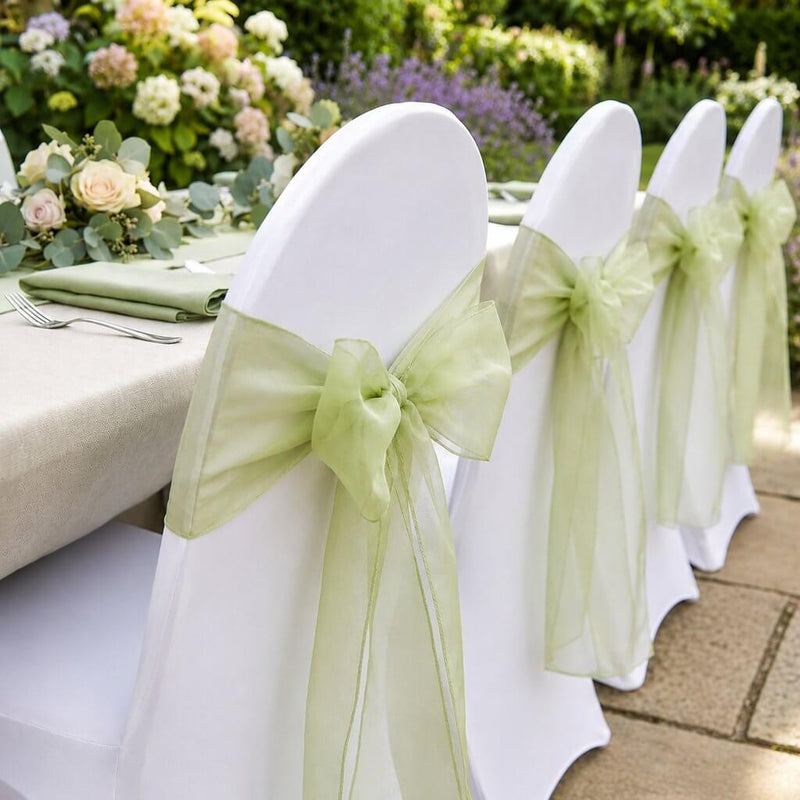 White chairs with sage organza sashes lined up outdoors - thumbnail number 4