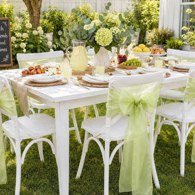White chairs with sage organza sashes at an outdoor table - thumbnail number 8