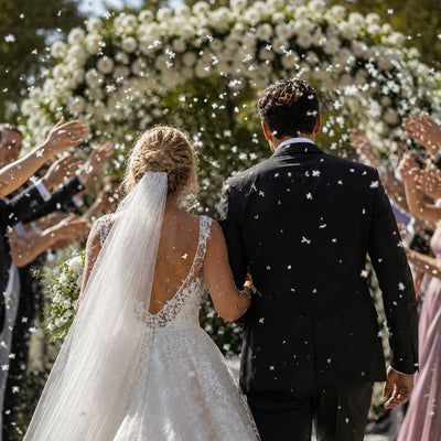Bride and groom walk as guests toss white confetti - thumbnail number 3