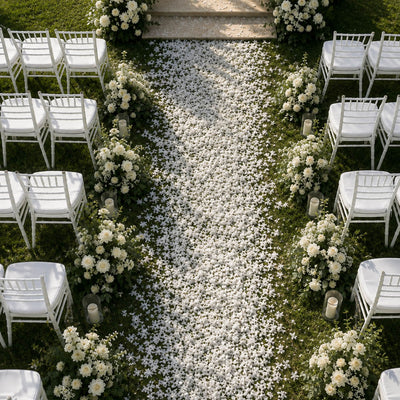Outdoor wedding aisle lined with white chairs, floral arrangements, and scattered confetti - thumbnail number 6