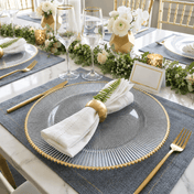 Glass charger with gold rim and napkin on a blue placemat at a formal dinner table - thumbnail number 4