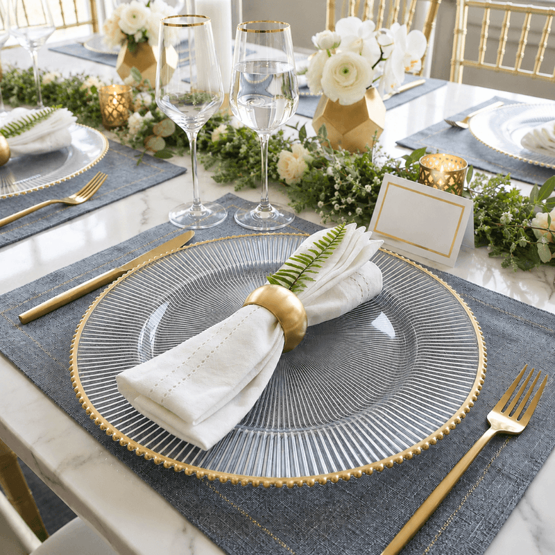 Glass charger with gold rim and napkin on a blue placemat at a formal dinner table - thumbnail number 4