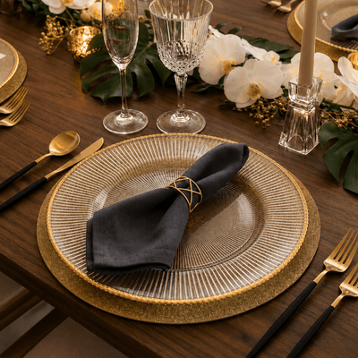 Glass charger with gold rim and dark napkin on a wooden table set for a formal dinner - thumbnail number 3
