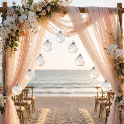 Iridescent glass ornaments hanging from a draped wedding arch on a beach - thumbnail number 4
