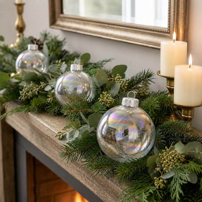 Iridescent glass ornaments styled in a pine garland on a mantelpiece - thumbnail number 7