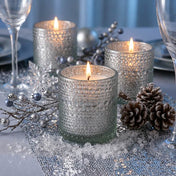 Pearly silver candle holders with winter decor and glowing candles on a festive table - thumbnail number 3