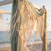 Clear glass ornaments hanging on a beach wedding arch with macrame decor - thumbnail number 4