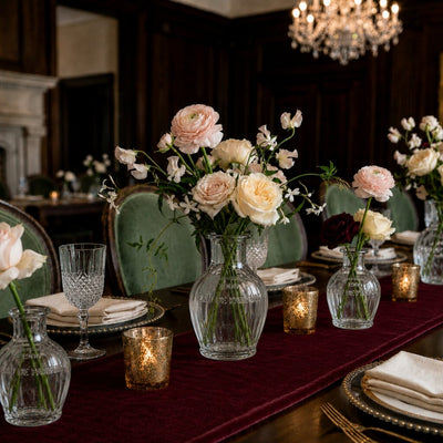 Floral arrangements in glass bottles on a dining table with a velvet runner - thumbnail number 4