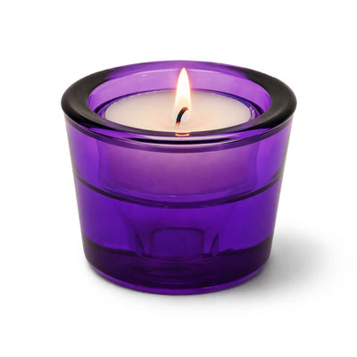 Lit tea light candle in a purple glass holder on a white background - thumbnail number 3