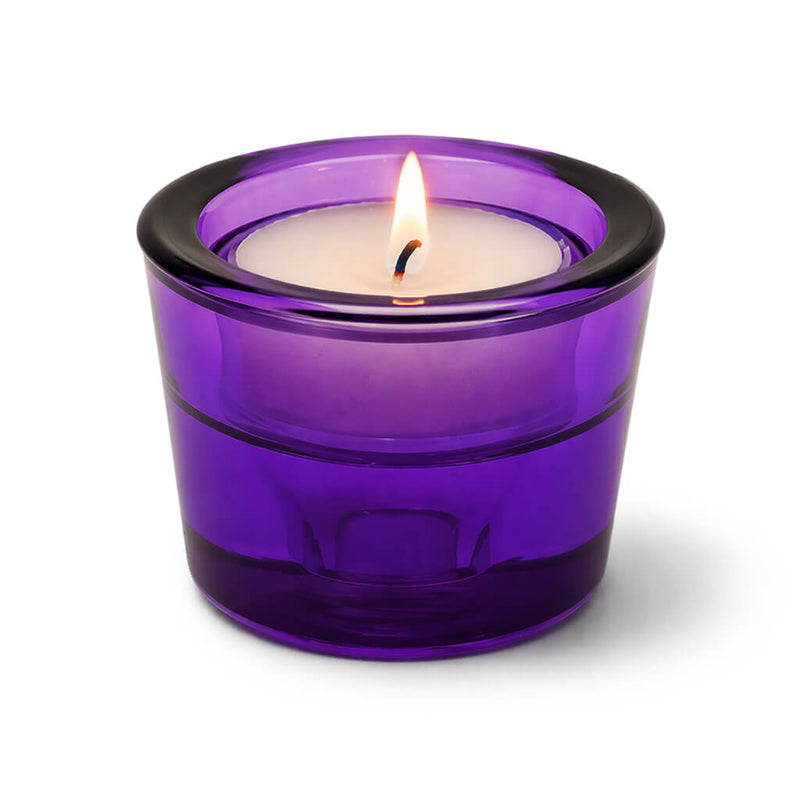 Lit tea light candle in a purple glass holder on a white background - thumbnail number 3