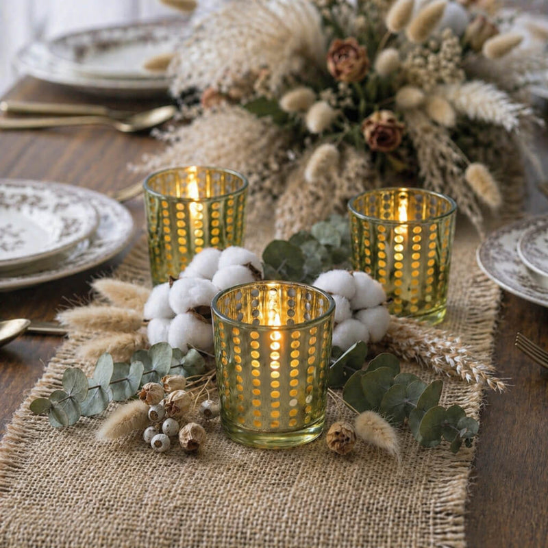 Three gold dotted glass candle holders with greenery and cotton on a burlap table runner - thumbnail number 4