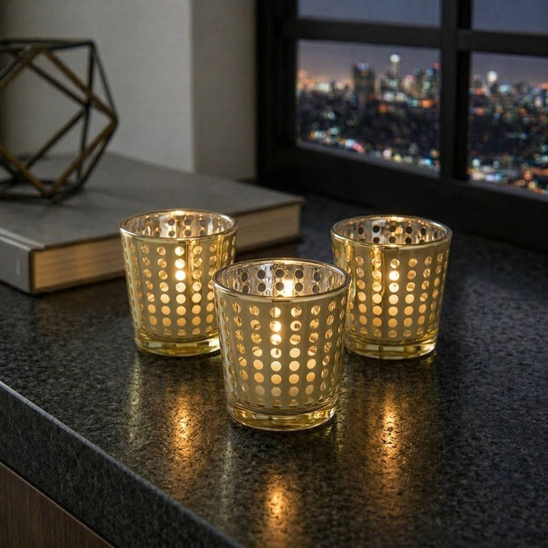 Three gold dotted votive holders lit on a granite counter with a city skyline in the background - thumbnail number 7