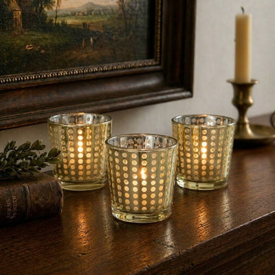 Three lit gold dotted votive holders on a wood mantel with an old book and framed painting - thumbnail number 8