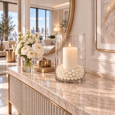 Glass hurricane vase holding a lit candle surrounded by ivory faux pearl beads on a console table - thumbnail number 10