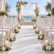 Wedding ceremony aisle lined with white chairs decorated with faux pearl strands, candles, and florals - thumbnail number 3