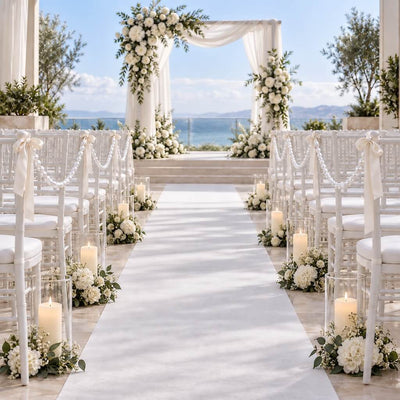 Wedding ceremony aisle lined with white chairs decorated with faux pearl strands, candles, and florals - thumbnail number 3