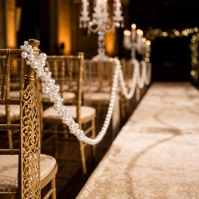 Gold wedding chairs decorated with white faux pearl string bead garlands along the aisle - thumbnail number 5