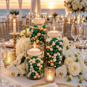 Glass vases filled with green, gold, and white pearls and floating candles. - thumbnail number 2
