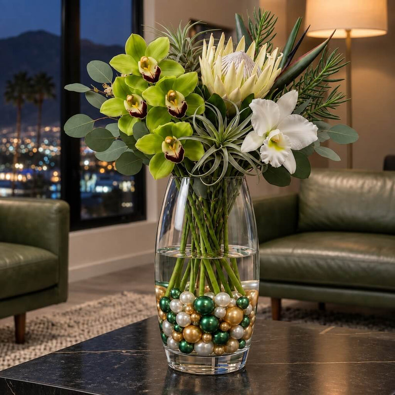 A tall glass vase with flowers sitting on a table, filled with green, gold, and white pearls - thumbnail number 7