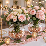Pink floral bouquets in glass bowl vases filled with rose gold and off-white pearls on a table - thumbnail number 4