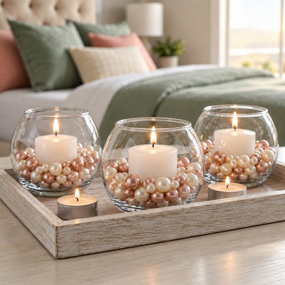 Lit candles in glass bowls filled with rose gold and off-white pearl beads in a cozy bedroom - thumbnail number 9