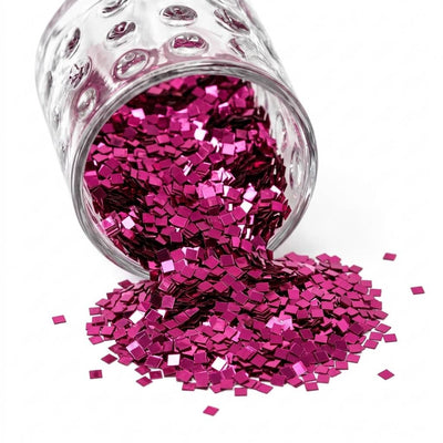 Metallic hot pink chunky glitter pouring out of a small glass jar onto a white surface - thumbnail number 1
