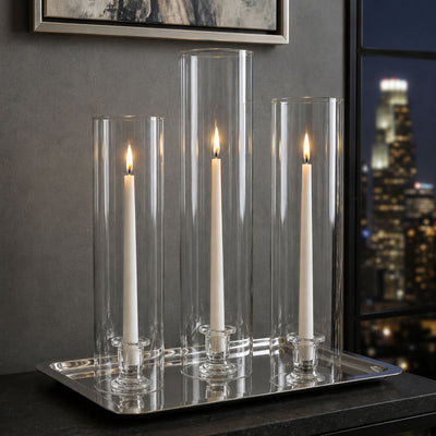 Lit white tapers with a chimney glass candle shade on a silver tray in an upscale interior - thumbnail number 7