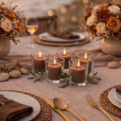 Five lit brown votive candles in glass holders on a table set with flowers and place settings - thumbnail number 5
